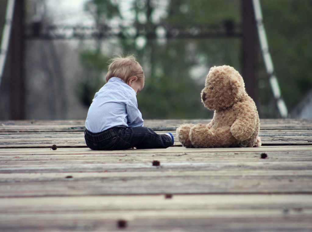 Divorce - boy sitting with brown bear plush toy on selective focus photo