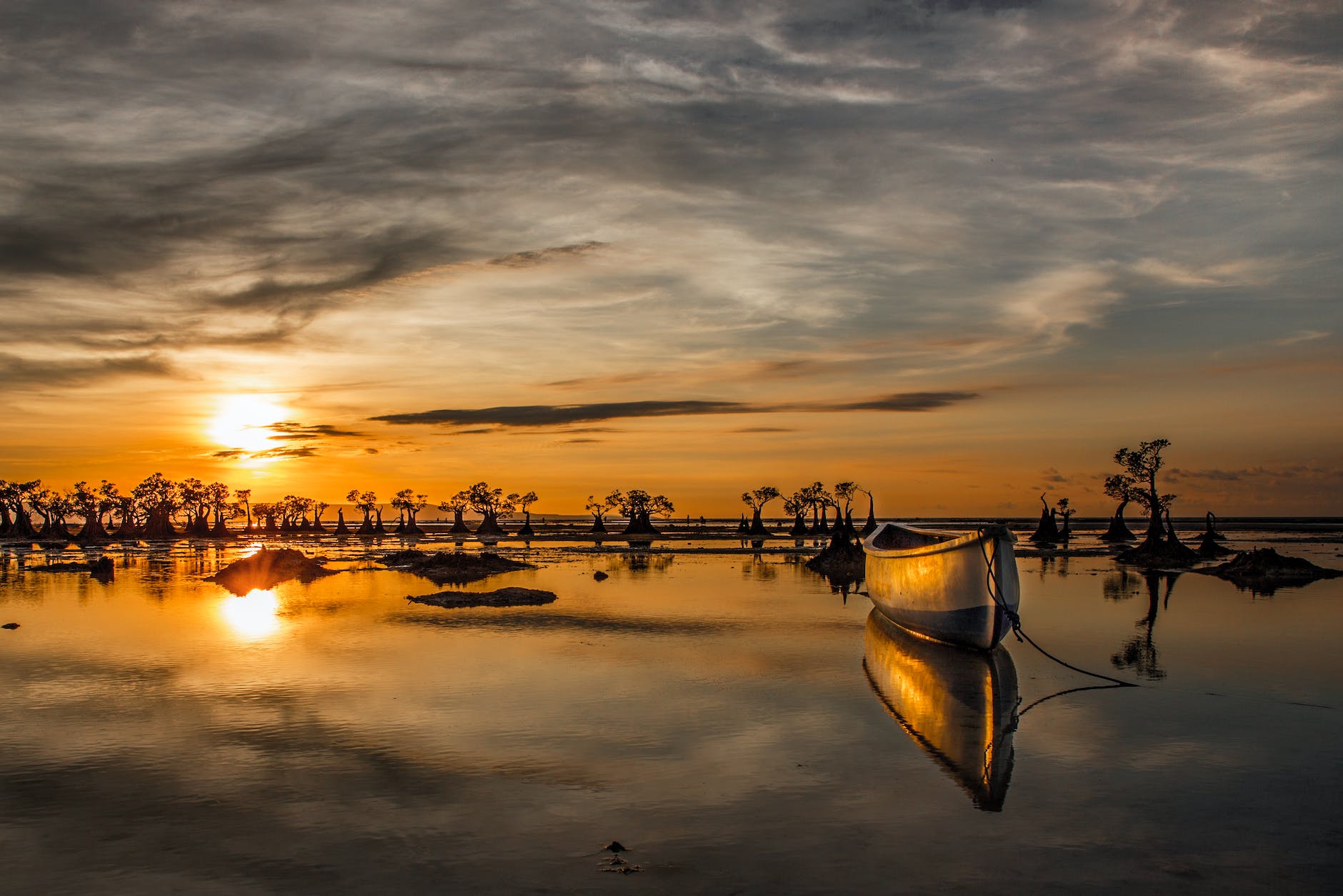 wooden boat on water under golden sky